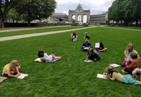 kinderen tekenen in het gras voor de triomfboog